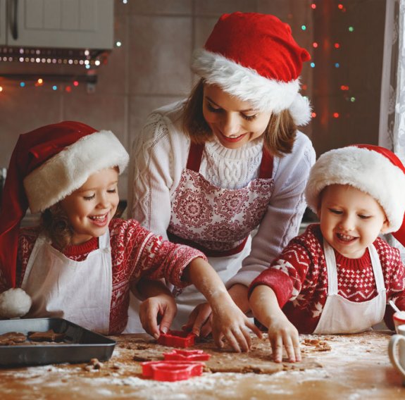 Weihnachtlich gekleidete Familie backt Plätzchen