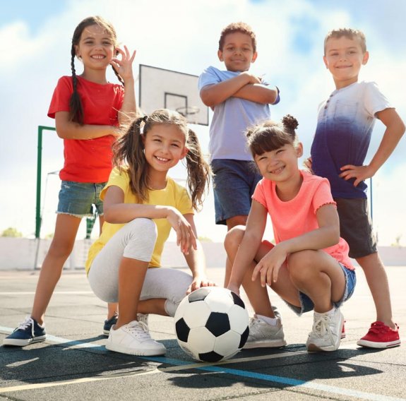 Kinder posieren mit einem Fußball