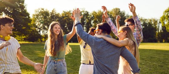 Eine Gruppe von jungen Erwachsenen geben sich gegenseitig ein High 5