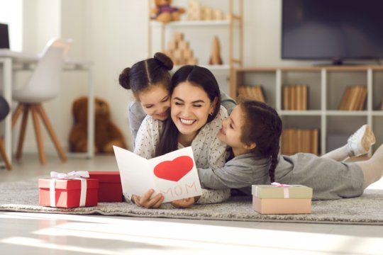 Eine Mutter mit ihren zwei Kindern sitzt auf dem Boden