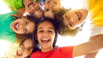 Kinder bilden mit ihren Köpfen eine Kreis und lachen. 