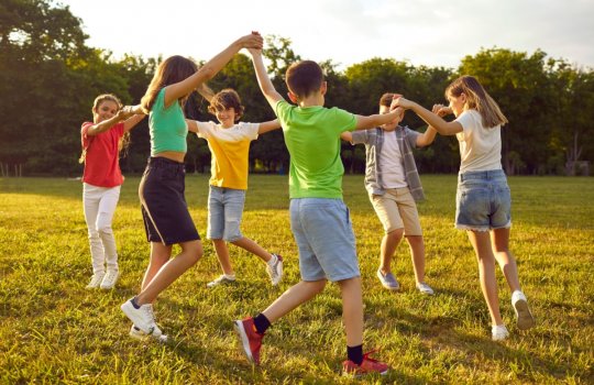 Kinder tanzen in einem Kreis zusammen