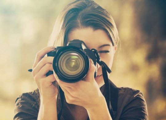 Eine Frau die gerade mit einer Kamera fotografiert