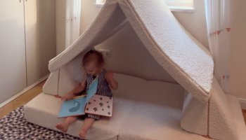 Ein Kind sitzt auf einem Spielsofa und liest ein Buch