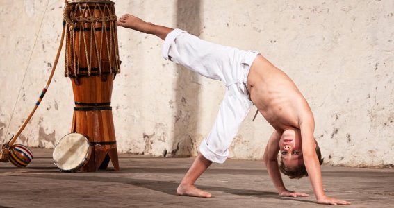 Kleiner Junge macht Capoeira.