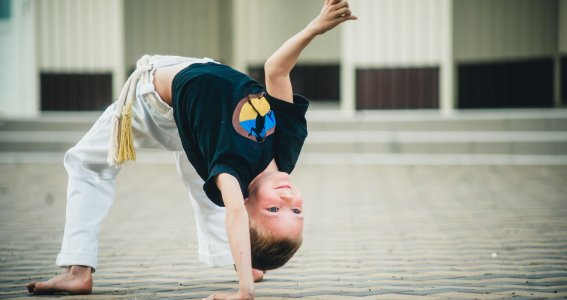 Kleiner Junge macht Capoeira.