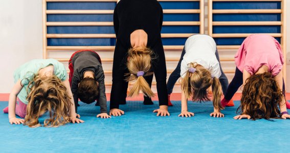 Kinder, die mit Lehrerin eine Übung ausführen 