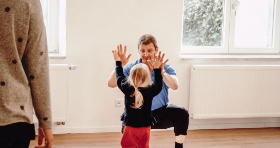 Kind und Trainer geben sich ein High-Five beim Turnen in München