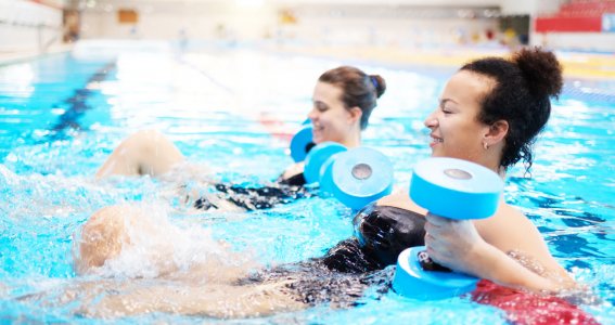 Erwachsene üben Wassersport mit Wasserhanteln aus.