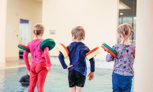 Kinder springen beim Kinderschwimmkurs für Anfänger ins Wasser