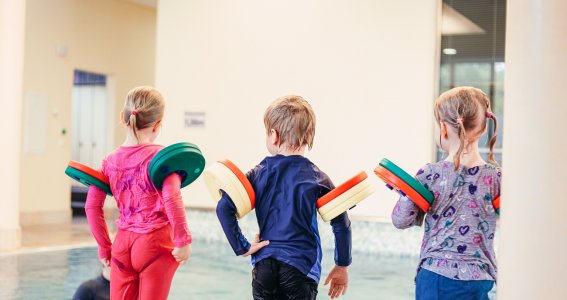 Kinder springen beim Kinderschwimmkurs für Anfänger ins Wasser