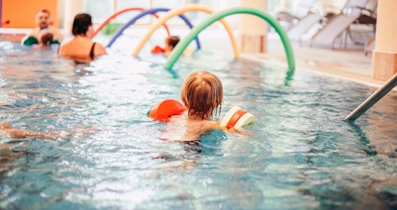 Junge sieht bunte Nudeln im Kinderschwimmkurs bei Aquabell