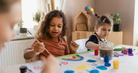 Drei Kinder malen am Tisch mit Pinseln