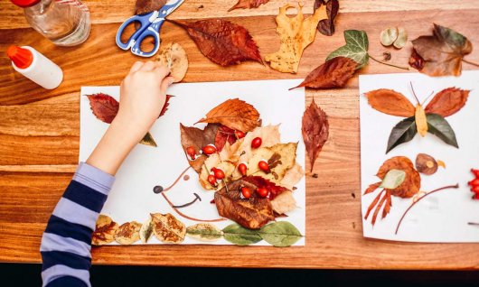 Kinder basteln mit verschiedenen Blättern.