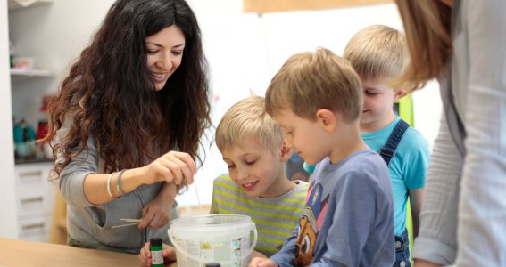 Kunstlehrerin und Kinder mischen im Malunterricht Farben.