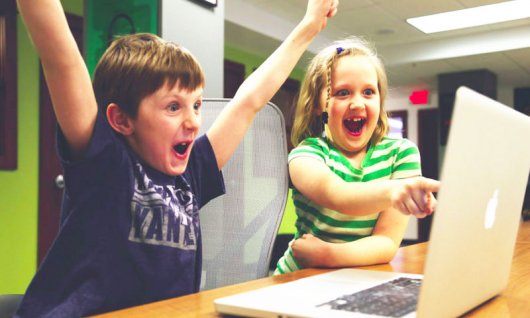 Zwei Kinder freuen sich vor dem Laptop