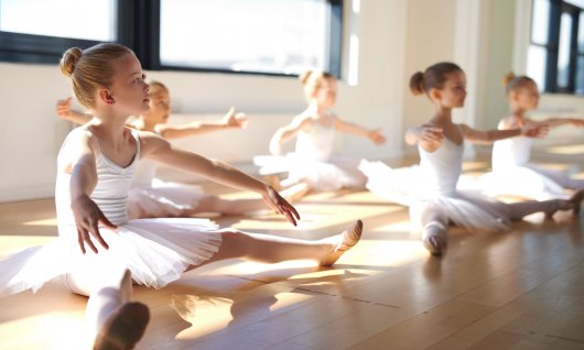 Mädchen sitzen im Tütü auf dem Boden. 