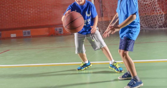 Zwei Buben spielen in einer Turnhalle Basketball