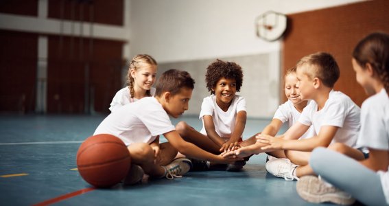 Eine Gruppe von Kindern sitzt im Kreis in einer Sporthalle