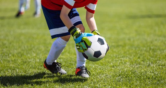 Ein Junge legt einen Fußball auf das Fußballfeld