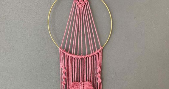 Rosaner Makramee Traumfänger hängt an einer Wand