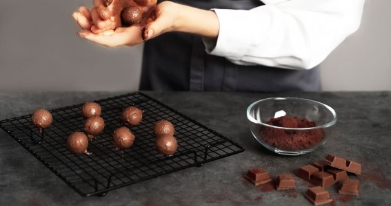 Mann formt Pralinenkugeln aus Schokolade