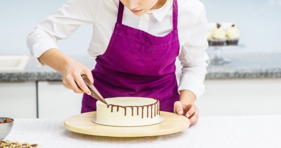 Eine junge Frau dekoriert eine Torte mit Schokoladenglasur