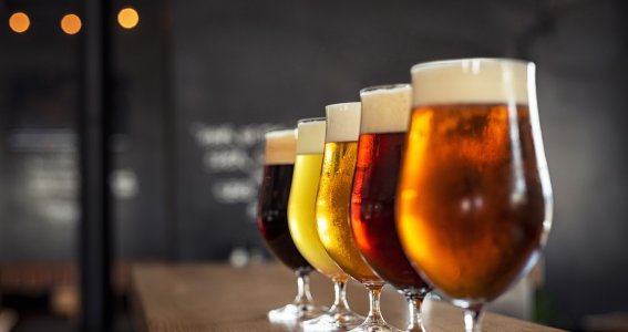 Fünf Gläser mit unterschiedlichen Biersorten in einer Linie gereiht