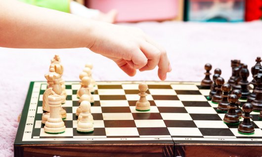 Schachbrett und kleines Kind macht den zweiten Schachzug