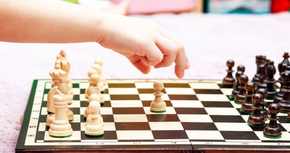 Schachbrett und kleines Kind macht den zweiten Schachzug