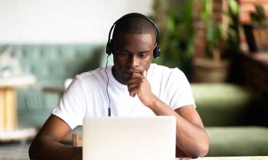 MS Office lernen für Studenten online Ein junger Mann mit Kopfhörern schaut konzentriert in seinen Laptop