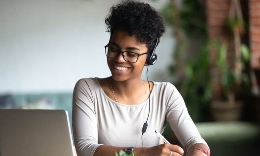 Online Kurs Wissenschaftliches Arbeiten für Studenten Eine junge Frau schreibt Notizen vor dem Laptop