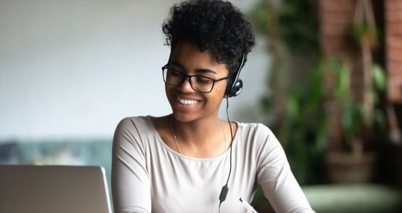 Eine junge Frau schreibt Notizen vor dem Laptop