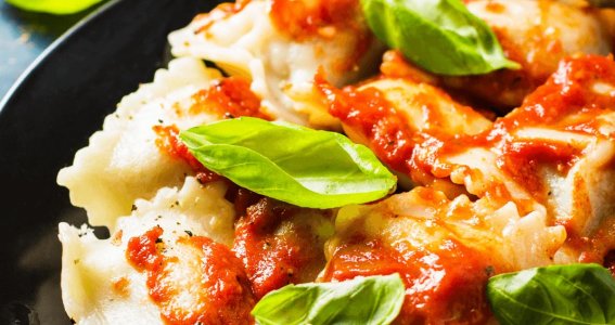 Teller mit Ravioli, Tomatensoße und Basilikum