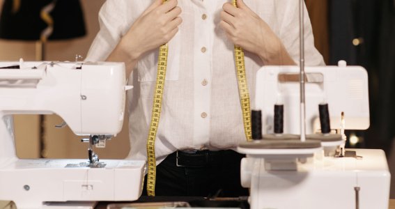 Eine Frau steht vor einer Nähmaschine und einer Overlock