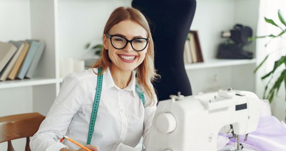 Eine lachende Frau sitzt vor der Nähmaschine