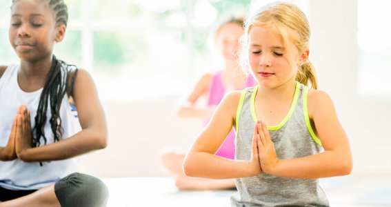 Drei Kinder meditieren beim Kinderyoga