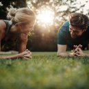 Mann und Frau machen auf einer Wiese Fitness