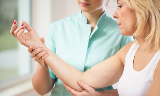 Eine Frau hält untersuchend den Arm einer anderen Frau