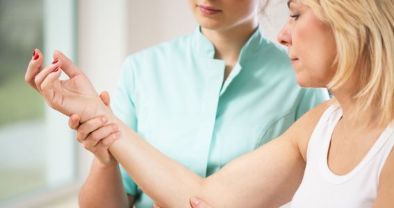 Eine Frau hält untersuchend den Arm einer anderen Frau