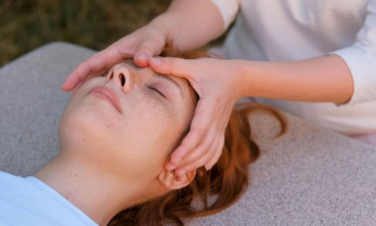 Eine Frau massiert den Kopf einer liegenden Frau