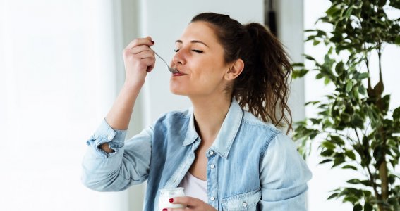 Eine Frau isst genüsslich einen Joghurt 