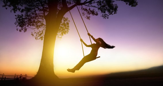 Eine Frau sitzt auf einer Schaukel, die auf einem Baum montiert ist