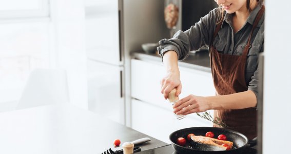 Eine Frau kocht ein Stück Fisch und Gemüse