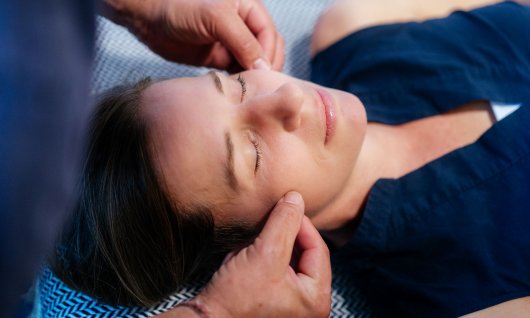 Ein Mann massiert den Kiefer einer Frau