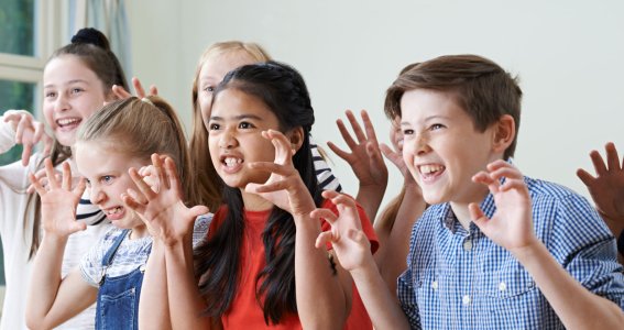 Kinder machen Theatergrimassen.