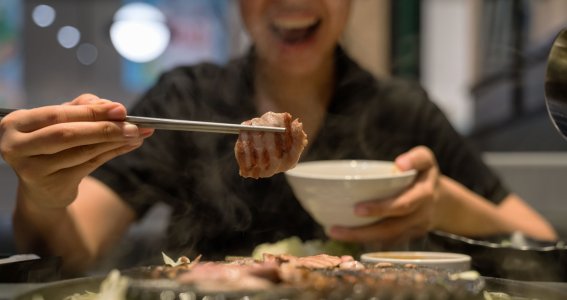 Mann, der ein Stück Fleisch auf den Grill legt 