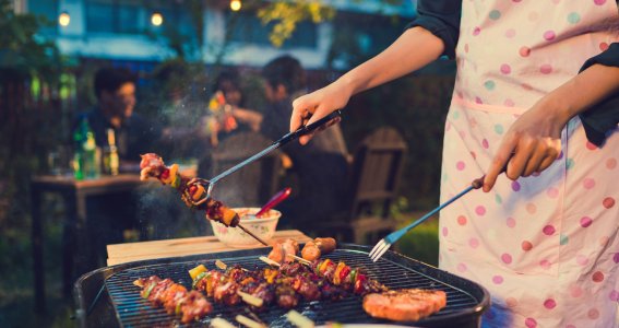 Frau am Grill und Fleisch auf dem Grill 