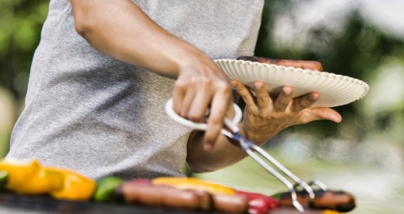 Frau am Grill und Fleisch, Gemüse auf dem Grill 