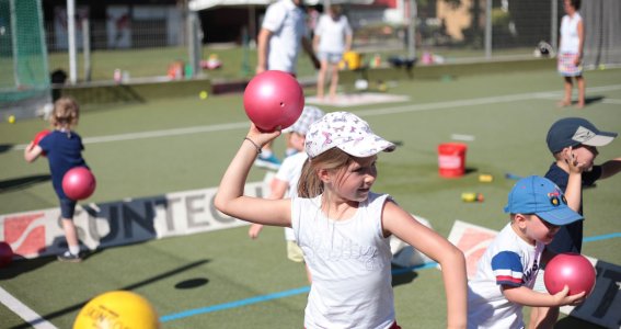 Kinder spielen mit Bällen und ein Mädchen wirft den Ball